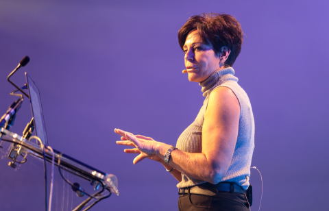 Motivational speaker Penny Mallory on stage with lecturn and microphones